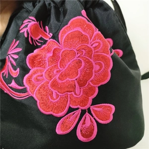 Close-up of intricate floral embroidery on black satin drawstring bucket bag detail
