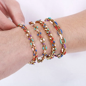Dettaglio di ciondoli in smalto colorato su bracciali a catena cubana in acciaio dorato