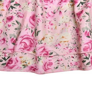 Close-up of pink floral print fabric with roses and detailed hem stitching on the garment