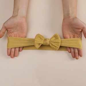 Elastic mustard yellow nylon bow headband for infants showing stretchable ribbed fabric