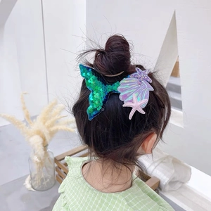Detail shot of sequin mermaid tail, shell and starfish hair clips worn by a girl
