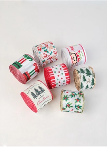 Detail view of seven rolls of Christmas ribbons with festive patterns on white background