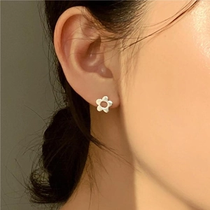Close-up of minimalist 925 sterling silver flower stud earring worn by a female model