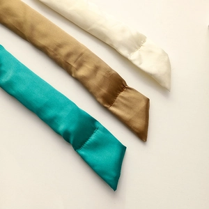 Three silk heatless hair rollers in blue, bronze, and beige shown on a neutral background