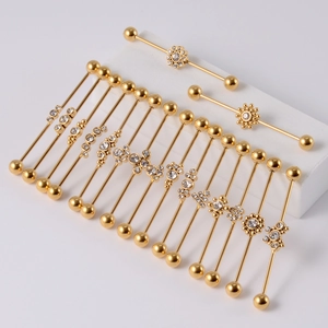 Golden 16G industrial barbells with flower motifs and sparkling crystals on stands