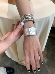 Detail view of wide cuff bracelets with hammered texture and minimalist metal finish