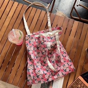 Detailed view of a vintage floral cotton canvas tote bag with pink roses on a wooden table