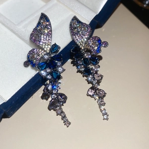 Close-up of blue and purple zircon butterfly tassel earrings on a velvet jewelry box