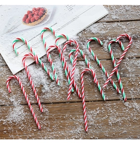 Detail of red and white striped candy cane ornaments on a snowy wooden surface