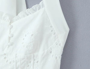 Détail d'une robe blanche avec broderie anglaise florale et boutons recouverts