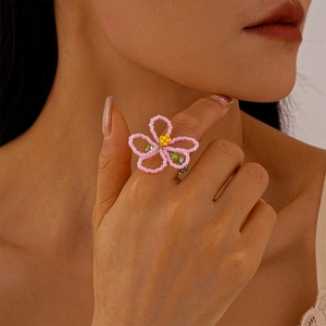Macro shot of a handmade flower bead ring with pink petals and yellow core for women
