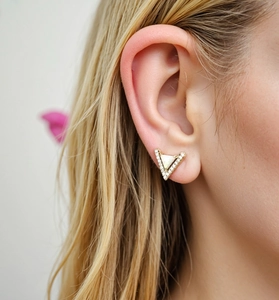 Macro shot of triangle stud earring with opal and crystals worn on earlobe