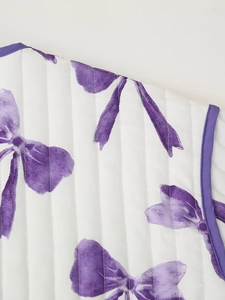 Macro detail of white quilted jacket with purple bow print and delicate piping edge