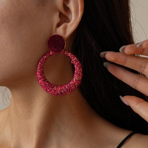 Close-up of pink flocked circular earrings with a fuzzy texture on a female model
