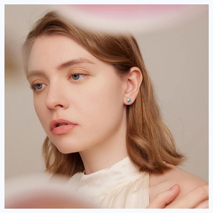 Close-up of minimalist silver stud earrings featuring turquoise stones on a model ear