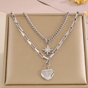 Detail of silver layered necklace with star and heart charms on a jewelry tray