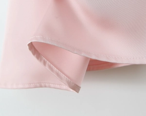 Vue détaillée de l'ourlet en satin rose avec texture lisse et coutures soignées de robe