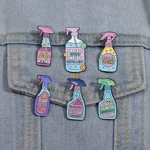 Set of six colorful enamel spray bottle pins with creative humorous slogans on denim jacket