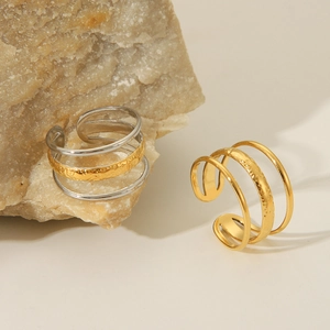 Close-up of three-layer 18K gold plated steel ring with hammered texture on natural stone