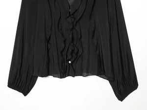 Détail d'une blouse noire à col en V avec volants sur le devant et boutons centraux