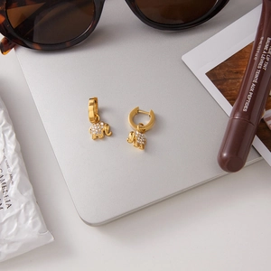 Golden elephant pendant earrings with sparkling rhinestones on a stylish white desk