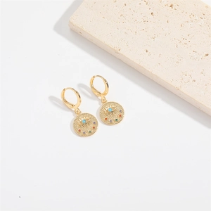 Detail of golden drop earrings featuring a round coin charm with a colorful evil eye motif