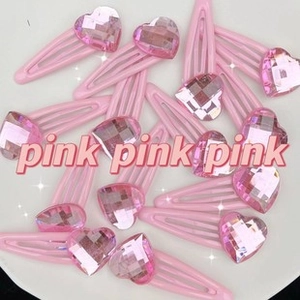 Detail of pink heart-shaped crystal hair clips with glossy finish on white background