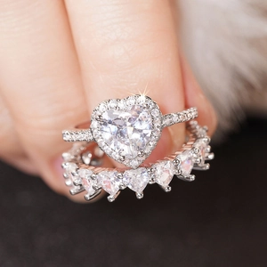 Close-up of sparkling heart-shaped zircon rings on finger for wedding jewelry sets