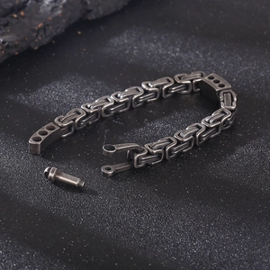 Detailed view of the interlocking chain links and unique buckle closure on this black steel bracelet