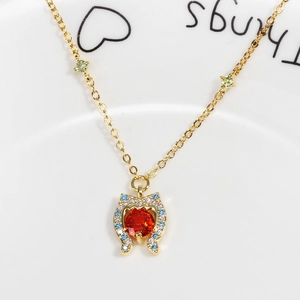 Macro detail of golden necklace featuring a red circular stone with blue and white accents