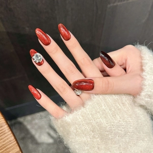 Cat eye press-on nails in deep red with rhinestone accents and elegant almond shape