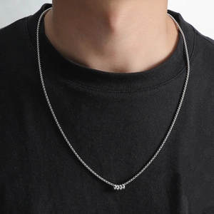 Minimalist silver chain necklace with a small cylindrical pendant shown on a model