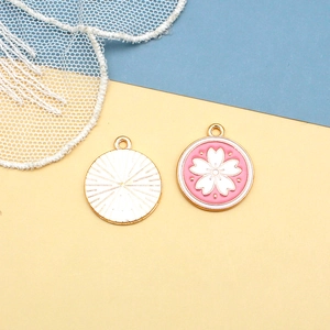 Detailed macro view of pink cherry blossom enamel charms with polished golden metallic finish