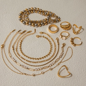 Flat lay of 18K gold and silver jewelry sets with necklaces, bracelets and zircon rings