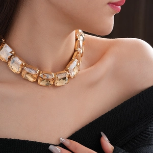 Dettaglio della collana girocollo dorata con grande cristallo color champagne su modella