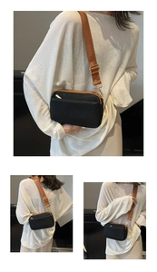 Detail showing a black crossbody bag with wide brown strap and elegant gold hardware