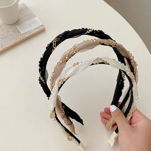 Detailed close-up of woven pearl and gold chain headbands in black, beige, and white