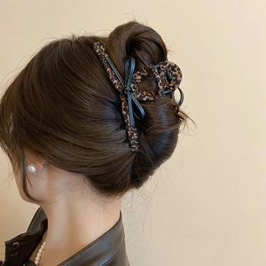 Detail view of large leopard print hair claw clip with black ribbon bow on hair