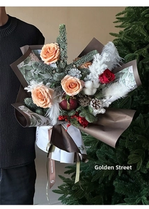 Detail of Christmas flower bouquet with roses cotton and pine cones in festive wrapping