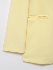 Detail of yellow blazer showing smooth woven fabric texture on sleeve and pocket