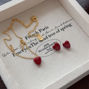Close-up of red heart zircon necklace and earrings set in a beige jewelry gift box