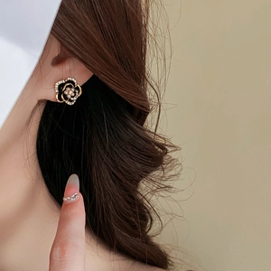 Detail of flower stud earrings featuring black enamel petals and a small pearl center