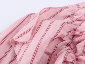 Detailaufnahme von rosa gestreiftem Stoff mit Rüschenkanten und feiner Verarbeitung