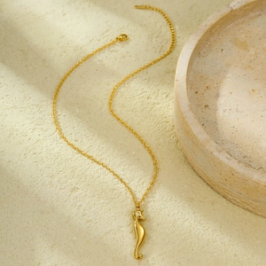 Detailed close-up of golden seahorse pendant necklace with a small sparkling diamond eye