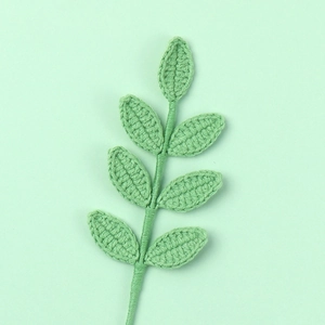 Handmade crochet light green seven-leaf branch on a matching minimalist background