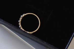 Macro shot of a thin gold ring with pearls and small crystals in a black jewelry box