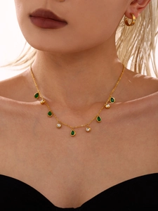 Detailed view of a gold-plated teardrop fringe necklace with emerald green crystals