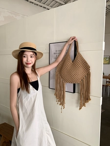 Dettaglio in primo piano della borsa bohémien all'uncinetto con maglia e lunghe frange.