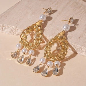 Detail of vintage gold earrings with hollow weaving, pearls, and teardrop crystals