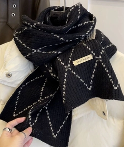 Close-up of black checkered knit scarf with white rhombus patterns and handmade label